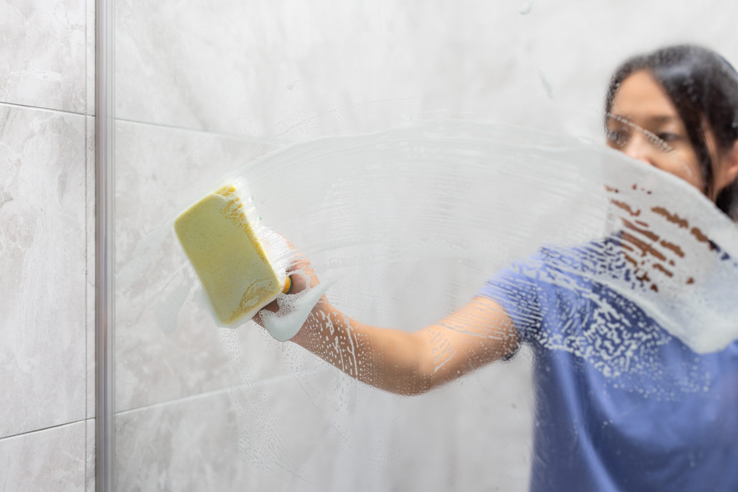Lady Cleaning Bathroom Mirror